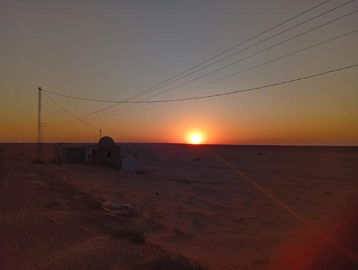 An open desert road with the sun rising on the horizon