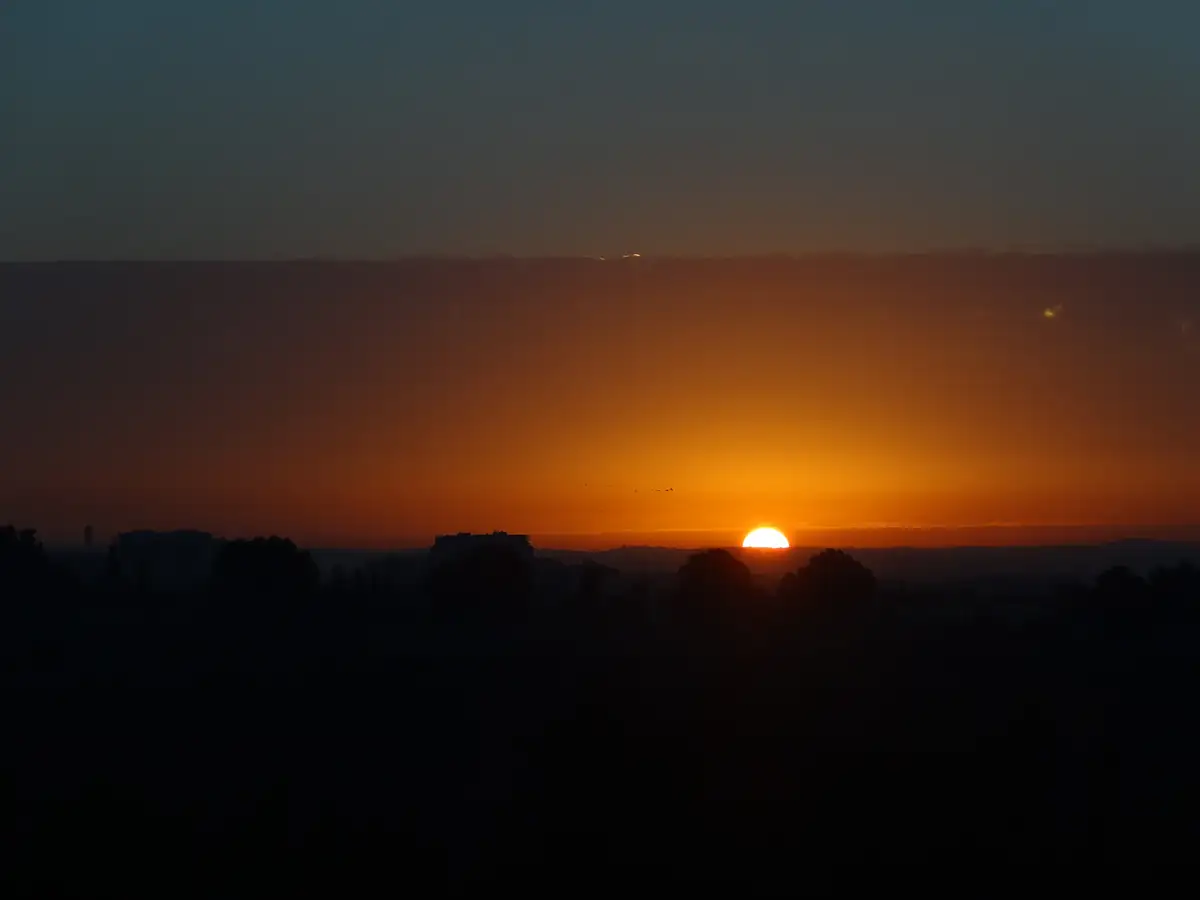 The sun rising over the city in an orange sky